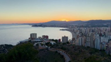 Benidorm kıyı şehrinde nefes kesici panoramik bir günbatımı sahnesi, canlı ve çarpıcı renklerini gözler önüne seriyor.