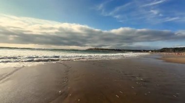 Nefes kesici bir sahil manzarası. Yanında dalgalar ve yukarıdaki parlak, renkli bir gökyüzü.