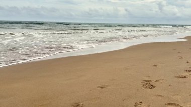 Yumuşak, sıcak kumlarla, yumuşacık dalgalarla ve güzel, sakin, bulutlu gökyüzüyle karakterize edilmiş sakin bir sahil.
