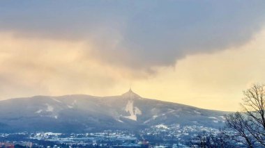 Bulutlu gökyüzünün altında uzanan muhteşem bir dağ zirvesi doğa aşıkları için ideal bir sahne oluşturuyor.