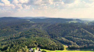 Kesinlikle nefes kesici bir hava manzarası dalgalı bir gökyüzünün altındaki kayan tepeleri ve yemyeşil ormanları gösteriyor.