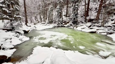 Karla kaplı kayalar ve uzun ağaçların yer aldığı inanılmaz sakin bir kış nehri sahnesi, gerçek güzellikleri gözler önüne seriyor.
