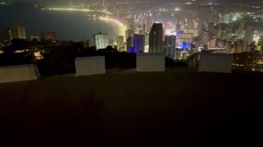 Canlı bir şehir siluetinin nefes kesici manzarası geceleri aydınlanıyor, modern mimari ve parlayan ışıklar sergileniyor..