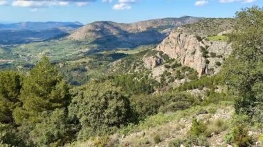 Nefes kesici manzara kayalık tepeleri, yemyeşil vadilerin yanında sergiliyor, hepsi yukarıdaki parlak mavi gökyüzünün altında.