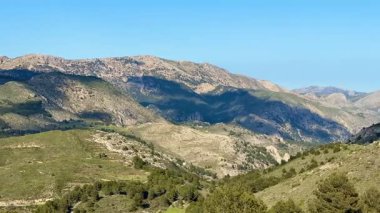 Nefes kesen manzaralar, yuvarlanan tepeler ve görkemli dağlar canlı mavi ve geniş bir gökyüzüne karşı kurulmuş.