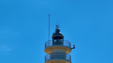 Çarpıcı bir deniz feneri, canlı mavi gökyüzüne karşı dimdik ve gururlu bir şekilde duruyor, herkese yol göstermeyi ve güvenliği simgeliyor.