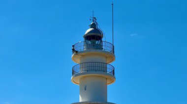 Resmedilmeye değer bir deniz feneri canlı mavi gökyüzüne karşı dimdik ayakta duruyor. Muhteşem sahil görüntüleri için ideal.