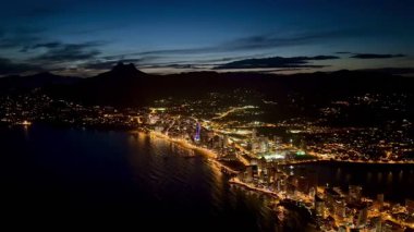 Göz kamaştırıcı bir hava manzarası canlı bir sahil şehri güzel ışıklarla süslenmiş canlı bir gece hayatı sergiliyor.