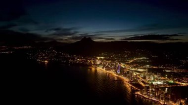 Bu güzel alacakaranlık manzarası çarpıcı şehir ışıklarıyla karışık bir şekilde aydınlatılmış canlı bir kıyı şehrini gözler önüne seriyor.