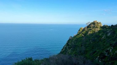 Uçsuz bucaksız okyanusun berrak mavi gökyüzünün altındaki yemyeşil uçurumdan nefes kesici ve çarpıcı manzarası.