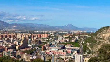 Şehir manzarasının, görkemli dağların ve yukarıdaki açık mavi gökyüzünün çarpıcı panoramik manzarasının tadını çıkar.
