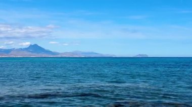 Göz kamaştırıcı ve güzel bir kıyı manzarası engin okyanusu, uzak görkemli dağları ve berrak mavi gökyüzünü gösteriyor.