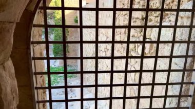 Büyüleyici bir taş pencere. Karmaşık bir metal ızgarayla çerçevelenmiş. Dışarıdaki yemyeşil manzarayı gözler önüne seriyor.