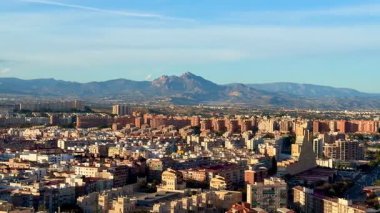 Nefes kesici, nefes kesici bir hava manzarası. Yakınlardaki görkemli dağların eşlik ettiği canlı bir şehir manzarasını vurguluyor.