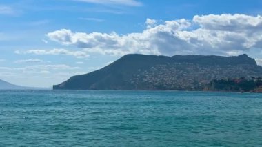 Sakin suların ve görkemli kıyı dağlarının berrak mavi gökyüzünün altında nefes kesici manzarasını deneyimleyin.