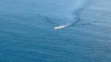 Bir tekneyi yakalayan bir hava görüntüsü sakin mavi sularda uyanıyor, deniz dinginliği ve macera sergiliyor..