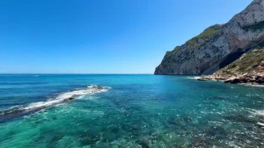 Çarpıcı ve nefes kesici bir deniz manzarası güzel turkuaz suları ve dramatik yüksek uçurumları tasvir ediyor.