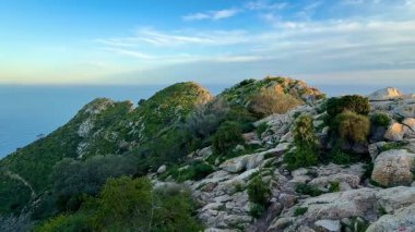 Şafakta sakin okyanusu görkemli bir şekilde gören nefes kesici kayalık tepeleri keşfedin, doğa meraklıları için ideal.
