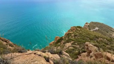 Canlı yemyeşil bir yeşil ile çevrili kayalık bir uçurumdan turkuaz suların nefes kesici manzarasının tadını çıkar.