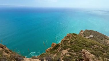 Kayalık bir uçurumdan gelen turkuaz denizin çarpıcı manzarası nefes kesici güzelliği ve cazibesini sergiliyor.