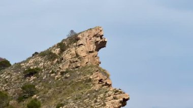 Göz alıcı bir kaya oluşumu, berrak bir gökyüzünün altındaki görkemli bir dağdaki insan profiline benziyor.