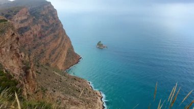 Gök mavisi deniz kıyısında yükselen kayalıkların büyüleyici güzelliğini yakalayın. Doğa ve seyahat temaları için idealdir.