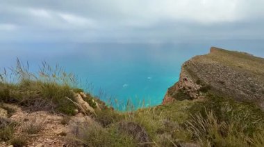 Çarpıcı kıyı manzaraları dramatik uçurumlar, yemyeşil otlar ve bulutlu bir günde sakin mavi sular sergiliyor.