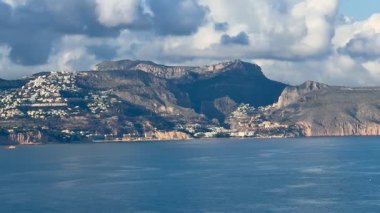 Büyüleyici güzellikte bir kıyı manzarası görkemli dağları, kabarık bulutları ve sakin suları sergiliyor.