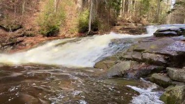 Kesinlikle nefes kesici bir manzara. Şelale gibi akan su sakin bir ormanda kayaların üzerinden akıyor.
