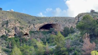 Göz kamaştırıcı bir mağaranın nefes kesici görüntüsü parlak mavi gökyüzü tarafından aydınlatılan canlı yeşil bir arazide gizlenmiş.