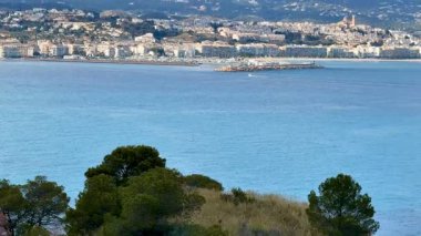 Deniz kenarındaki kıyı kasabasının göz kamaştırıcı manzarası. Arka planda berrak mavi sular ve dağlar var..