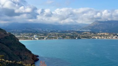 Güzel bir şekilde sergilenen nefes kesici kıyı manzarası dingin sular, yemyeşil tepeler ve büyüleyici bir ufuk çizgisi.