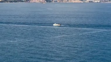 Sakin bir tekne süzülür ve uçsuz bucaksız mavi okyanusta parlak, berrak, güneşli gökyüzünün altında uçar gider.