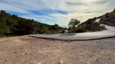 Güzel ve pitoresk dolambaçlı bir yol bulutlu bir gökyüzünün altındaki yemyeşil tepelerin arasından geçiyor.