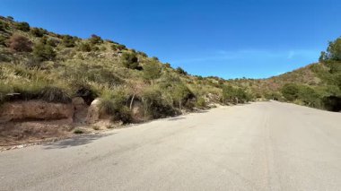Berrak mavi gökyüzünün altında yemyeşil yemyeşil ile çevrili sakin ve huzurlu bir dağ yolu.