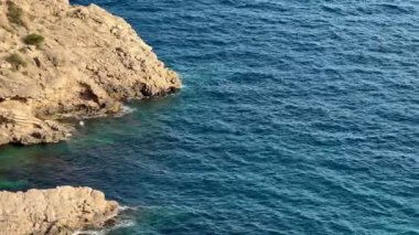Kayalık bir kıyı şeridinin güzel manzarası berrak mavi denizle buluşur, unutulmaz doğa görselleri için mükemmeldir.