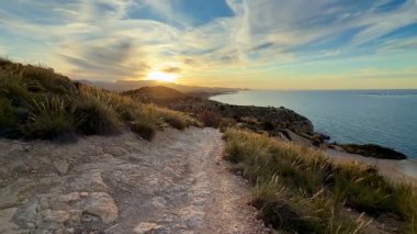 Deniz yüzeyinde gün batımının güzel yansımalarını barındıran kıyı şeridinin nefes kesici bir görüntüsü.