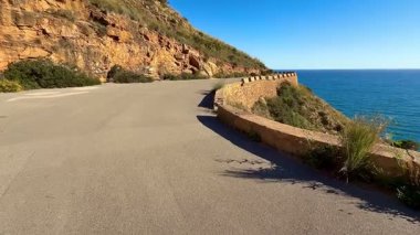 Kıyı yolu kayalıklar boyunca kıvrılır, canlı hissettiren güneşli bir günde nefes kesici okyanus manzarası sunar.