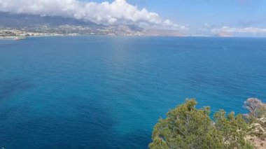 Turkuaz suları, yemyeşil yemyeşil ve etkileyici bulut oluşumlarıyla güzel kıyı manzarasının tadını çıkar.