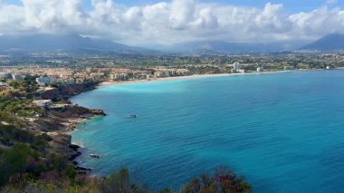 Güzel turkuaz suların ve yemyeşil yeşilliklerin yer aldığı sakin bir sahil şeridinin nefes kesici hava manzarası.