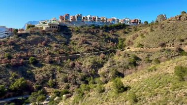 Görkemli yamaç manzarası, çarpıcı güzellikteki okyanus zeminine karşı modern evleri sergiliyor.