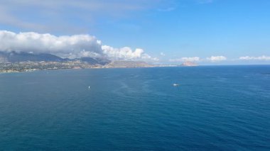 Resmedilmeye değer bir kıyı manzarası sakin suları, dingin gökyüzünü ve uzak görkemli dağları gösteriyor.