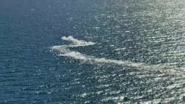 Titreyen bir okyanus yüzeyinde süzülen heyecan verici jet ski izlerini yakalayan dinamik hava çekimlerini tecrübe edin.