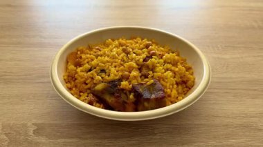 Lezzetli sarı pirinç, taze sebze ve sulu etle dolu canlı ve renkli bir kase.