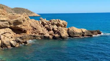 Güzel, sakin bir sahil manzarası göz kamaştırıcı mavi okyanus suları ve berrak bir gökyüzünün altındaki engebeli kıyı şeritleri