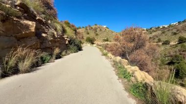 Huzurlu ve huzurlu bir yürüyüş yolu yemyeşil, yuvarlanan tepeler boyunca uzanır, doğal güzelliğin nefes kesici manzarasını sağlar.