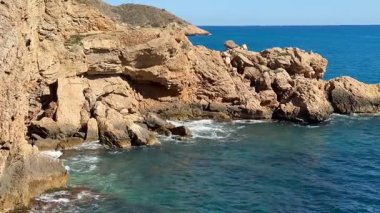 Huzurlu, sakin bir kıyı manzarası sakin ve çarpıcı mavi okyanus sularının yanında kayalık uçurumlar sergiliyor.