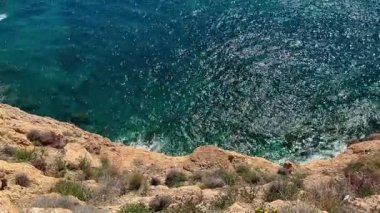 Büyüleyici bir sahil şeridi güzel bir günde parlak güneş ışığı altında parıldayan berrak turkuaz suları sergiliyor.