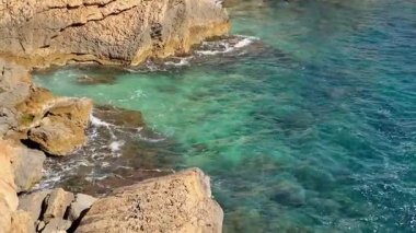 Okyanusun dingin, turkuaz sularıyla buluşan kayalık kıyıların nefes kesici ve büyüleyici görüntüsünü deneyimleyin.