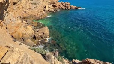 Göz kamaştırıcı ve güzel bir kayalık kıyı şeridi gururla turkuaz suyu sergiliyor hafif dalgaların yanında
